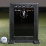 Ernest Sports golf launch monitor device on artificial turf with golf ball nearby, used for golf swing analysis and practice at home or in a golf simulator.