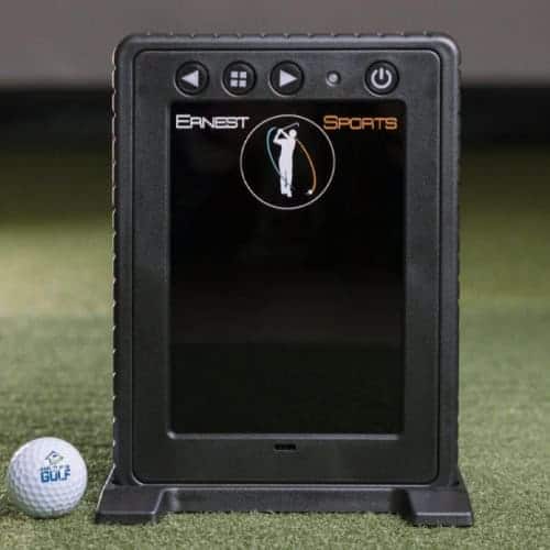 Ernest Sports golf launch monitor device on artificial turf with golf ball nearby, used for golf swing analysis and practice at home or in a golf simulator.