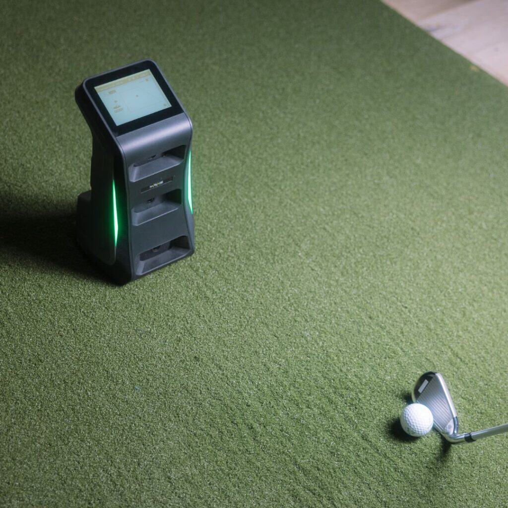 Advanced golf simulator launch monitor with touchscreen interface, placed on artificial turf, ideal for indoor golf practice and swing analysis.